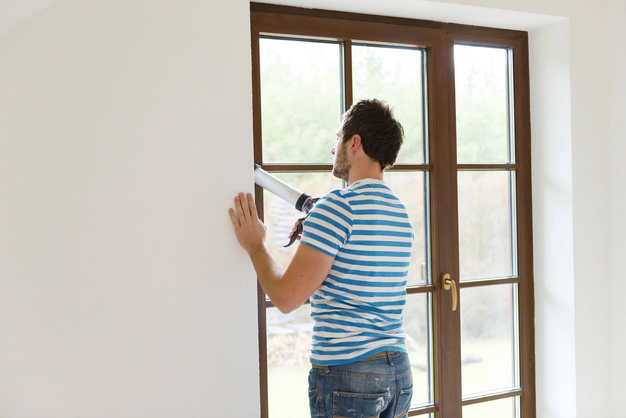 Man applying caulk around a window.