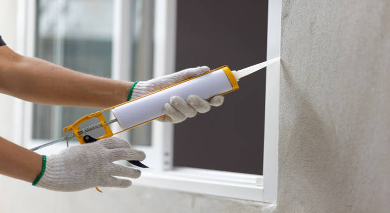 Applying sealant with a caulking gun.